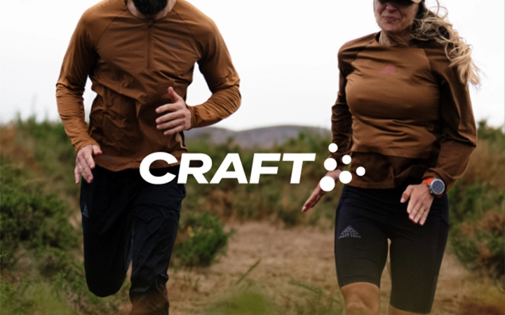 גבר ואישה רצים בשדה לבושים בבגדים של CRAFT עם לוגו במרכז